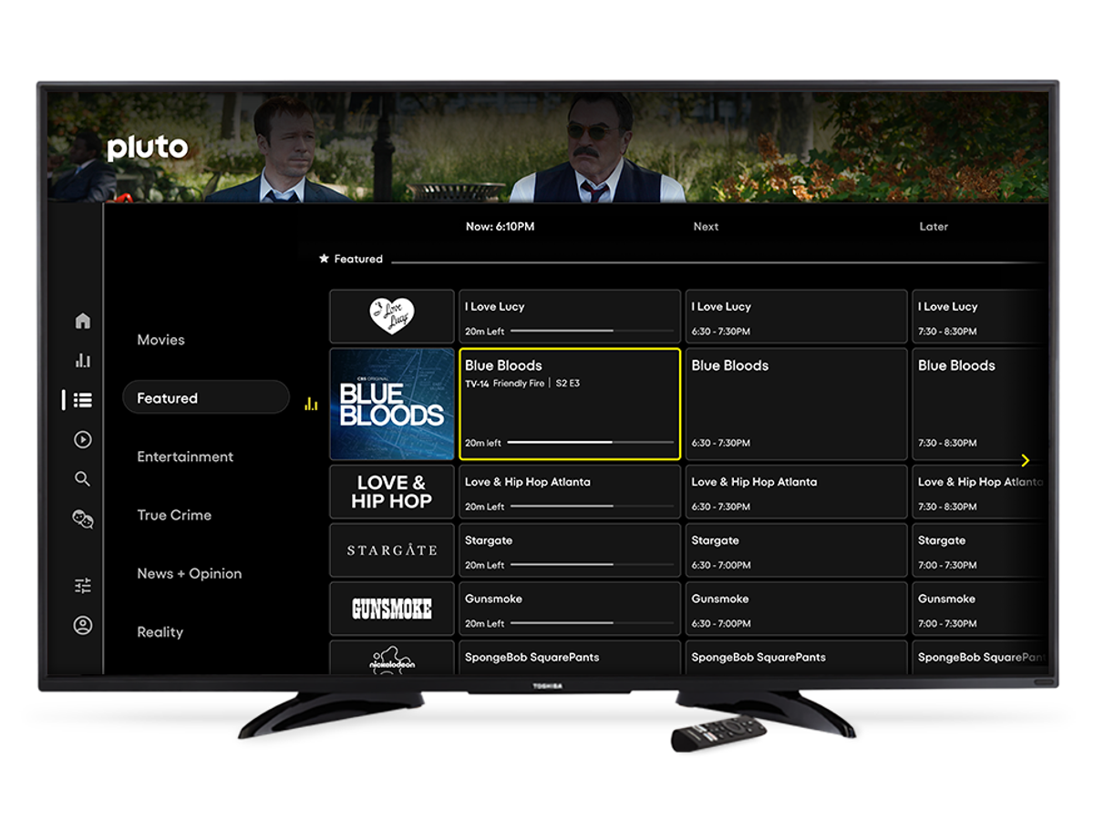 Smart TV displaying a live-channel guide, with a remote control